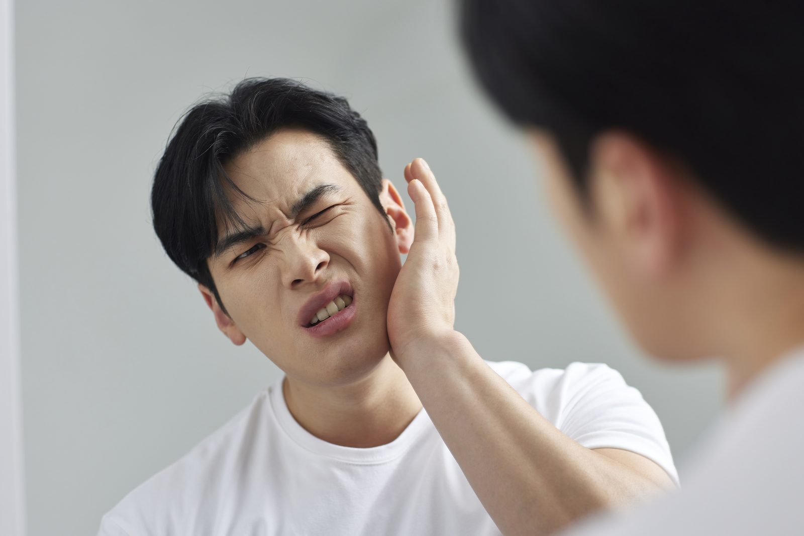 턱관절이 불편해 턱을 감싸고 있는 남성